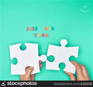 women hand hold empty large white puzzles and the inscription join our team on a green background, concept of recruitment