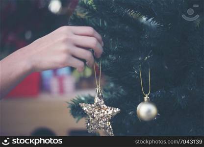 women hand setting decorations and gift boxes on Christmas tree
