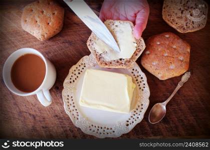 Women hand with a knife spreads butter on bread .Breakfast background .. Women hand with a knife spreads butter on bread .Breakfast background