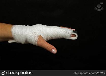 Women hand with finger crossed over rail stabilizing wrapped in elastic bandage, injury finger on a black background. Close, horizontal view.