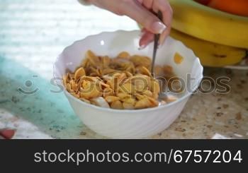Women hands are preparing cereal with milk for breakfast
