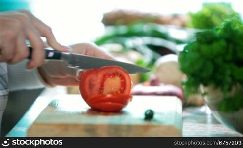 Women hands chopped tomato in the kitchen