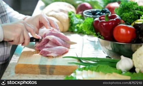Women hands cutting fresh pork meat in the kitchen