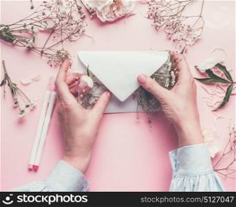 Women hands holding paper envelope filled with flowers , top view, flat lay.Wedding, invitation ,Valentine day, Mother&rsquo;s Day concept. Flat lay, top view, copy space