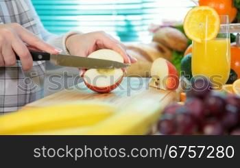 Women hands sliced red apple in the kitchen