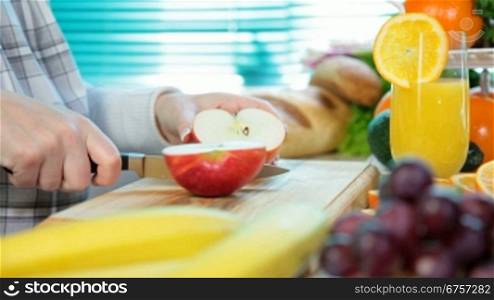 Women hands sliced red apple in the kitchen