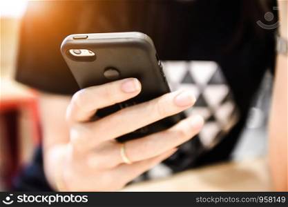 women holding smart phone on hand and seating against sunlight background,Technology mobile internet for everyday life using