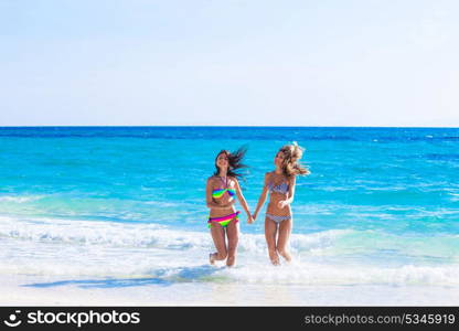 Women in bikni run to beach. Beautiful fit women in bikni run from tropical sea to beach