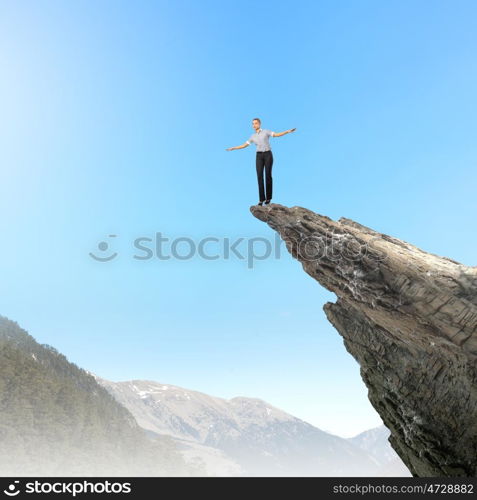 Women in business. Risky businesswoman standing on edge of rock