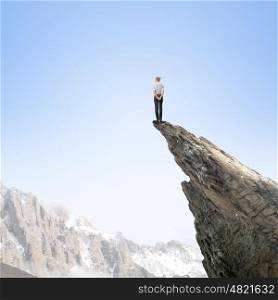 Women in business. Risky businesswoman standing on edge of rock