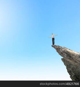 Women in business. Risky businesswoman standing on edge of rock