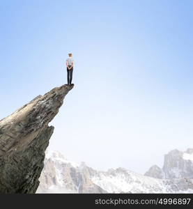 Women in business. Risky businesswoman standing on edge of rock