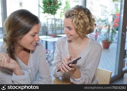 women in cafe looking at their smartphones