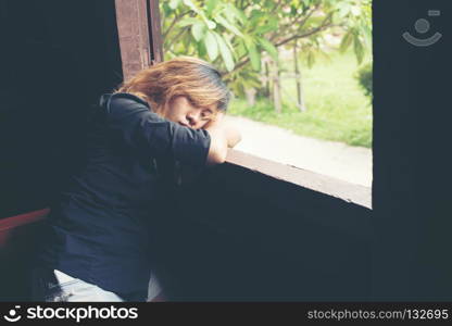 Women lifestyle concept : young sad woman sitting on bench beside window look to outside, sadness,loneliness.. Women lifestyle concept : young sad woman sitting on bench besid