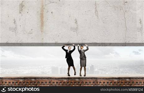 Women lifting wall. Two businesswomen lifting cement wall. Place for text