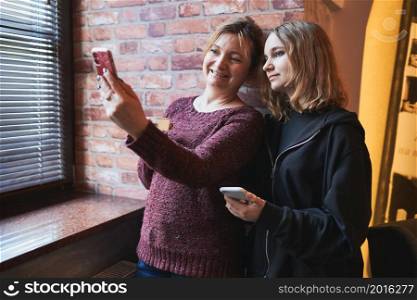 Women making video call on mobile phone. Taking selfie photo using smartphone. Connecting remotely with family and friends