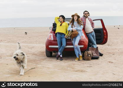 women man near car dog running beach