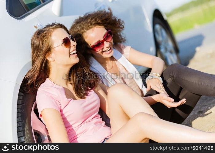 Women near car. Young pretty women sitting near white car at side of road