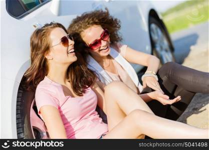 Women near car. Young pretty women sitting near white car at side of road