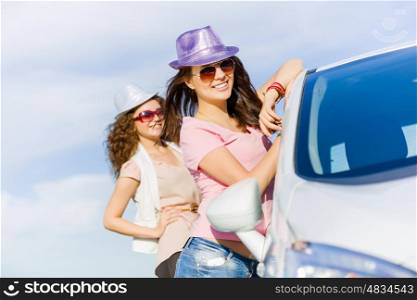 Women near car. Young pretty women standing near white car at side of road