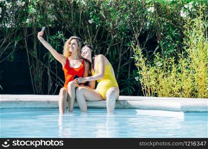 women of different races in bikinis having their photo taken at the edge of a swimming pool