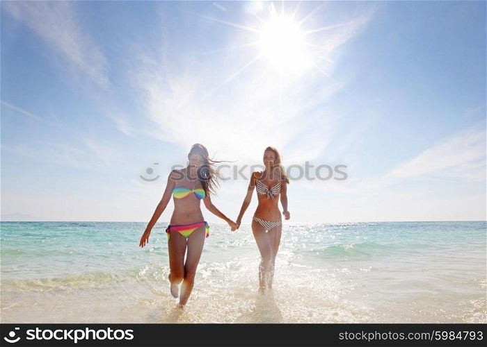 Women on beach. Two smiling women in bikini walking from sea to beach