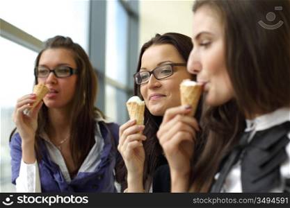women on foreground licking ice cream