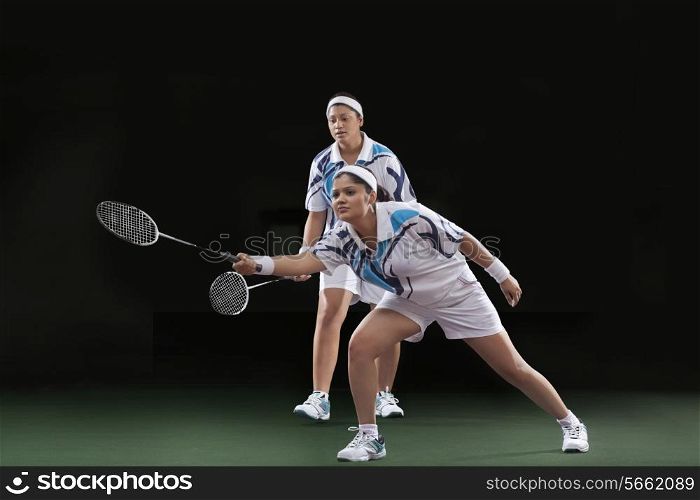 Women playing badminton isolated over black background