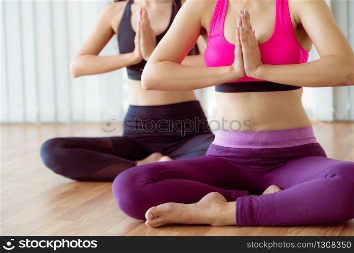 Women practicing yoga pose in fitness gym group class. Healthy lifestyle and wellness concept.