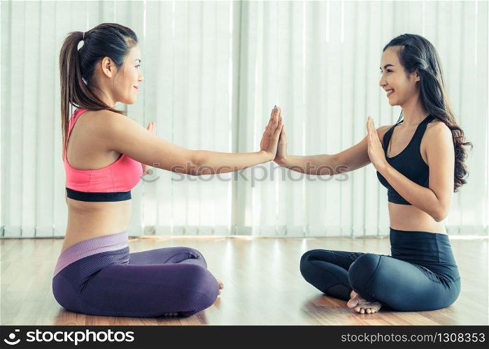 Women practicing yoga pose in fitness gym group class. Healthy lifestyle and wellness concept.