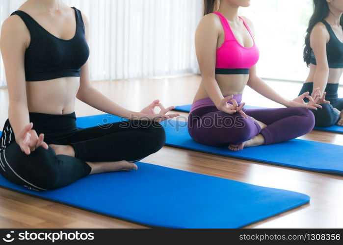 Women practicing yoga pose in fitness gym group class. Healthy lifestyle and wellness concept.