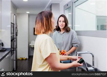 Women preparing healthy food and washing some vegetables in kitchen having fun, concept dieting nutrition.