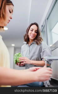 Women preparing healthy food and washing some vegetables in kitchen having fun, concept dieting nutrition.