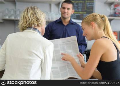 women reading newspaper in a bar