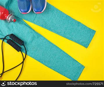 women's clothing and accessories for sports and fitness on a yellow background, top view, flat lay