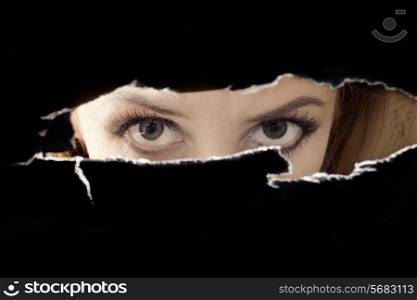 Women&rsquo;s eyes spying through a hole close up