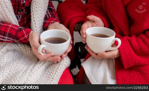 Women&rsquo;s hands are holding white cup of tea or coffee dressed in red and white festive clothes.. woman female holdingcup tea coffee red festive clothes christmas new year valentine