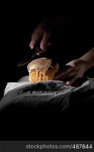 women's hands hold a knife over traditional Easter pastries, on the table is a gray linen napkin, black background