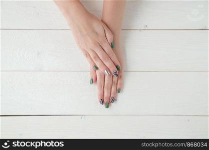 women's hands with a beautiful manicure on a light wooden background