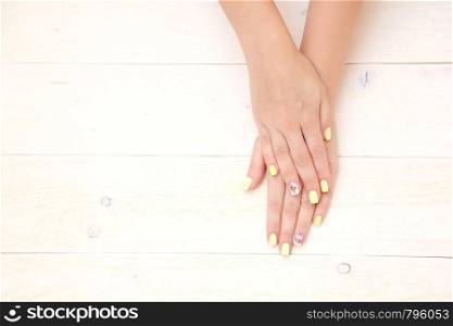 women's hands with a beautiful manicure with drawings of cakes and cherries on a light wooden background