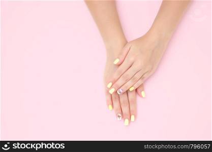 women's hands with a beautiful manicure with drawings of cakes and cherries on a pink background