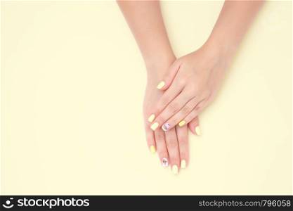 women's hands with a beautiful manicure with drawings of cakes and cherries on a yellow background