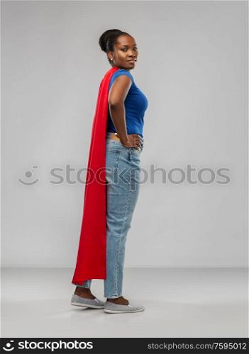 women&rsquo;s power and people concept - african american woman in red superhero cape over grey background. african american woman in red superhero cape