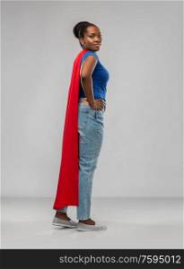 women&rsquo;s power and people concept - african american woman in red superhero cape over grey background. african american woman in red superhero cape