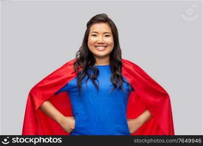 women&rsquo;s power and people concept - happy asian woman in red superhero cape over grey background. happy asian woman in red superhero cape