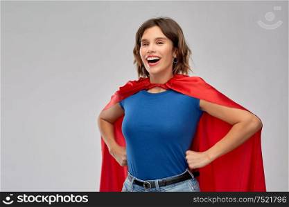 women&rsquo;s power and people concept - happy woman in red superhero cape over grey background. happy woman in red superhero cape