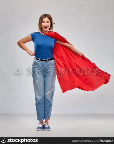 women&rsquo;s power and people concept - happy woman in red superhero cape over grey background. happy woman in red superhero cape