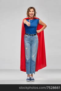 women&rsquo;s power and people concept - happy woman in red superhero cape showing thumbs up over grey background. happy woman in superhero cape showing thumbs up