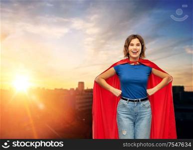women&rsquo;s power and people concept - happy woman in red superhero cape over sunset in city background. happy woman in red superhero cape over city sunset