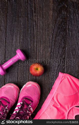 Women's sports bra,foot ware, Dumbbell and apple on dark wooden background. Fitness wear and equipment. Sport fashion, Sport accessories, Sport equipment. for healthy concept.